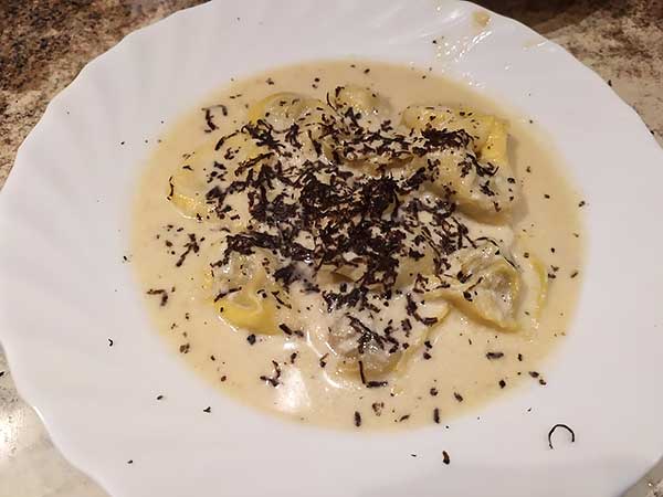 Imagen de un plato de raviolis con trufa rallada.