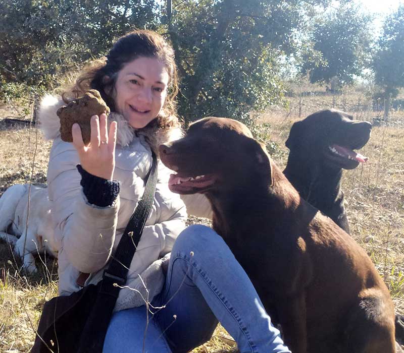 Mujer con perros labradores mostrando una trufa en el campo.
