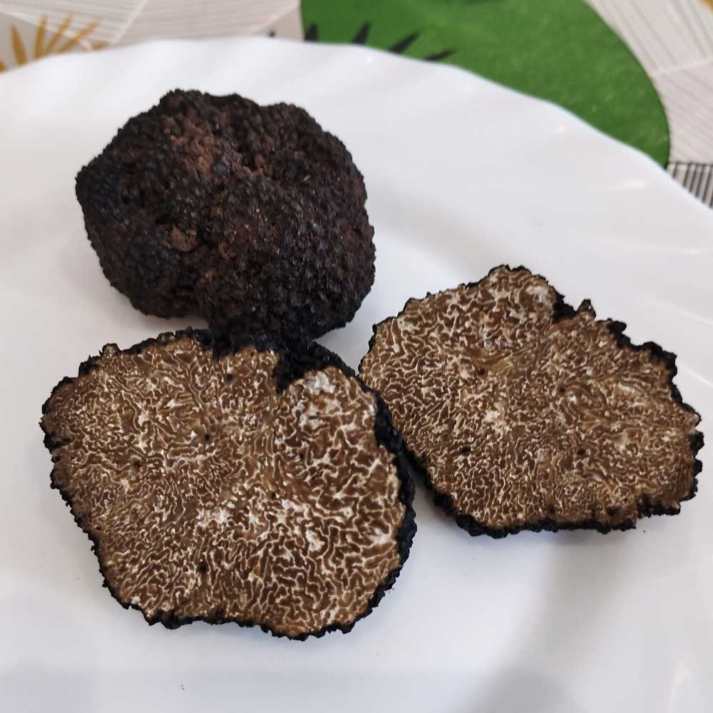 Trufa de otoño (Tuber uncinatum), una entera y dos mitades con vetas internas blancas.